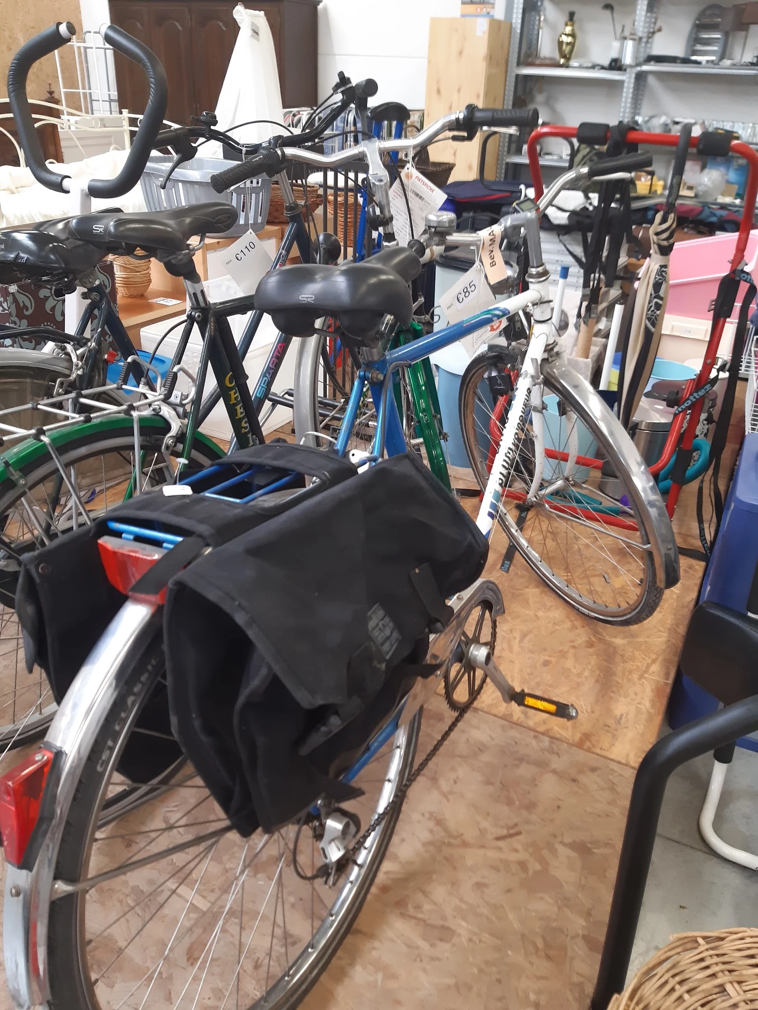 Verschillende tweedehandsfiетsen en fietsen met accessoires in de winkel