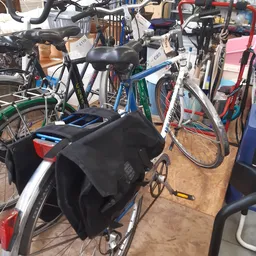 Verschillende tweedehandsfiетsen en fietsen met accessoires in de winkel