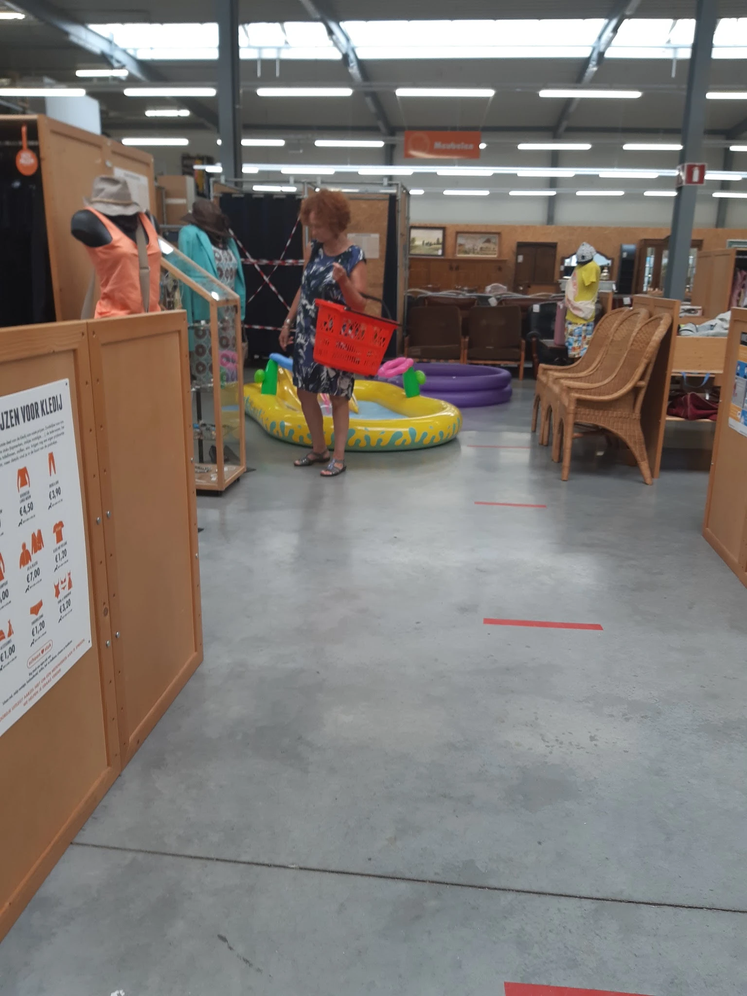 Winkelvloer met houten kastjes, gele en groene zitzakken, paarse speelkubus en rode markeringen op de grond