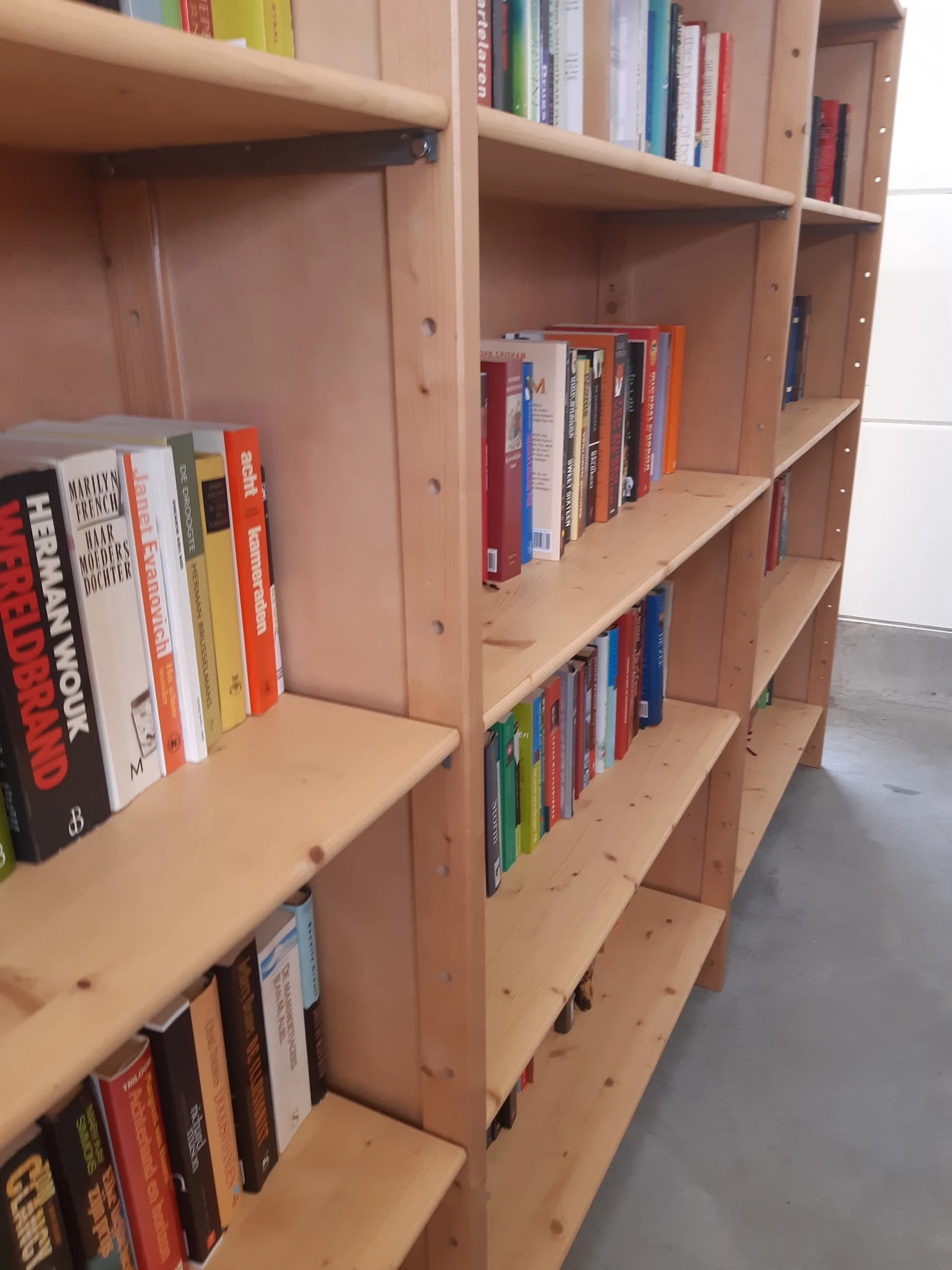 Houten boekenkasten met tweedehands boeken in verschillende kleuren en formats