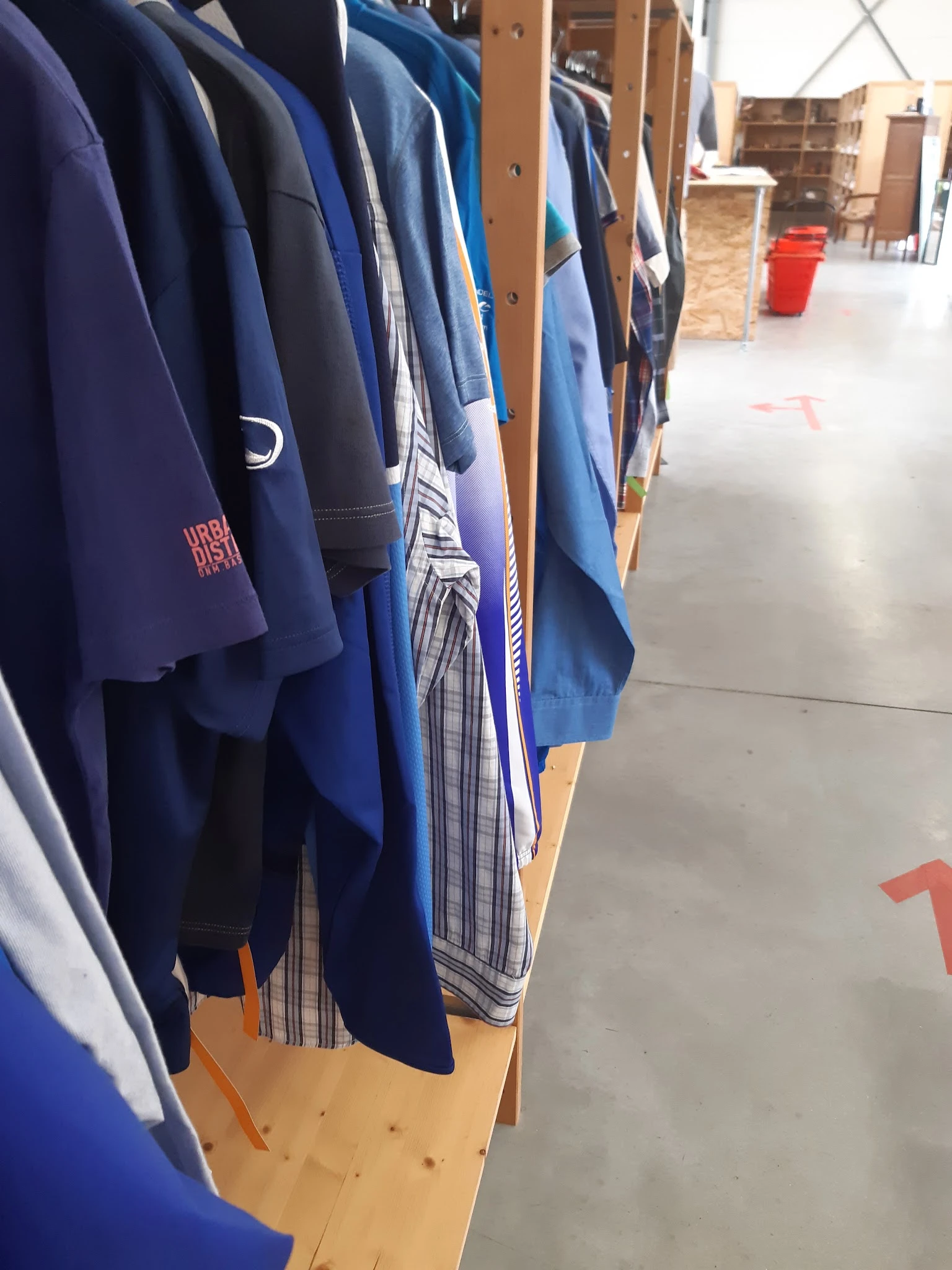 Rekken met tweedehands kleding, vooral blauwe en donkerblauwe kledingstukken
