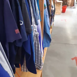 Rekken met tweedehands kleding, vooral blauwe en donkerblauwe kledingstukken