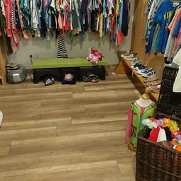 Winkelvloer met kledingrekken, pop-up display met kinderkleding en speelgoed, houtenplanken aan de grond