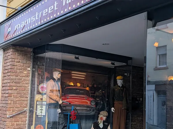 Vintage winkel met grote raamuitstalling met rode klassieke auto, mannekin en retro decorstukken