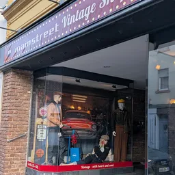 Vintage winkel met grote raamuitstalling met rode klassieke auto, mannekin en retro decorstukken
