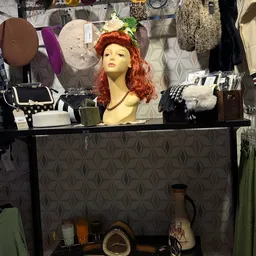 Vintage winkelwaar inclusief mannequin met rood haar, tassen, sieraden en kledingrekken op achtergrond
