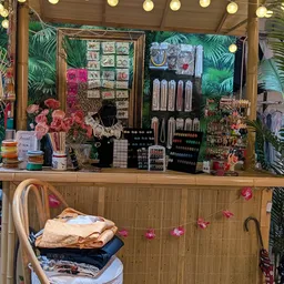 Toonbank met uitgestalde sieraden, kettingen, oorbellen en accessoires tegen een groene achtergrond met bloemen