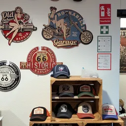 Witmuur met vintage Route 66 en garage decoraties, houten kastje met vintage petjes en baseballcaps
