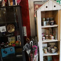 Vintage winkelkast met verschillende serviesgoed, decoratieve items en keramiek op houten planken