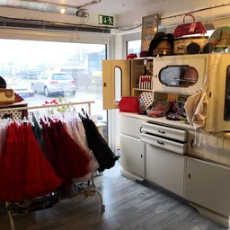 Vintage winkelinterieur met rode tutus aan rek, vintage fornuis en handtassen op display