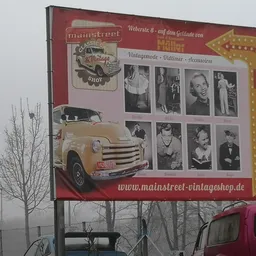 Groot reclamebord van vintage winkel met oude auto en zwart-witfoto's, langs straat met kale boom