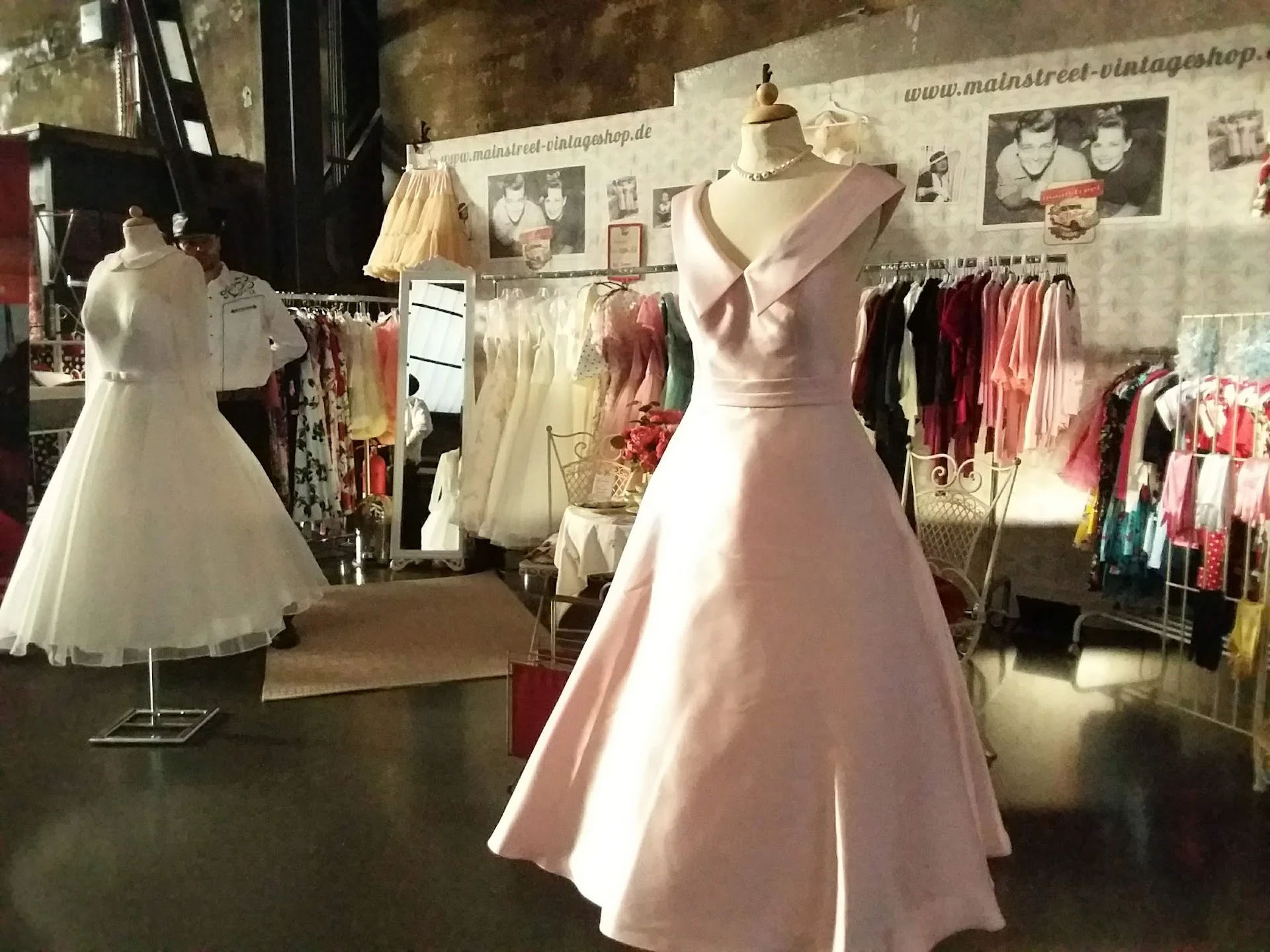 Vintage jurken op mannequins en aan rekken in de winkel, vooral witte en roze feestjurken
