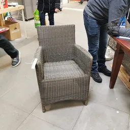 Grijze rotan fauteuil met kussen op de winkelvloer