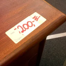 Prijskaartje met rode tekst op houten tafelblad
