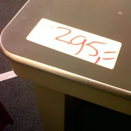 Prijskaartje met handgeschreven prijs 29,95 euro op een beige object