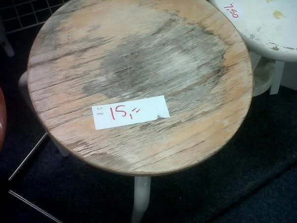 Ronde houten tafel met prijskaartje waarop '15?' staat geschreven