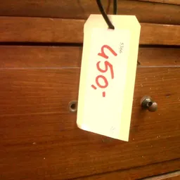 Prijskaartje met '€9,50' in rode letters aan een houten kast