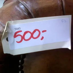 Prijskaartje met nummer 5445 en prijs 500;- op bruinen leren artikel