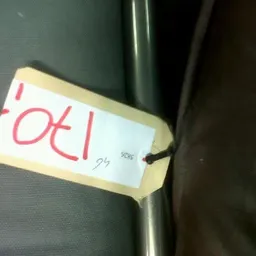 Gele prijssticker met rode handgeschreven tekst 'OEI' op een metalen staaf