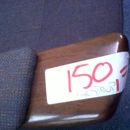 Houten armleun of meubeldeel met prijssticker waarop '150' en 'UITSTROOI' geschreven staat
