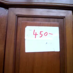 Wit papier met handgeschreven prijs '450-' op houten kastdeur geplakt