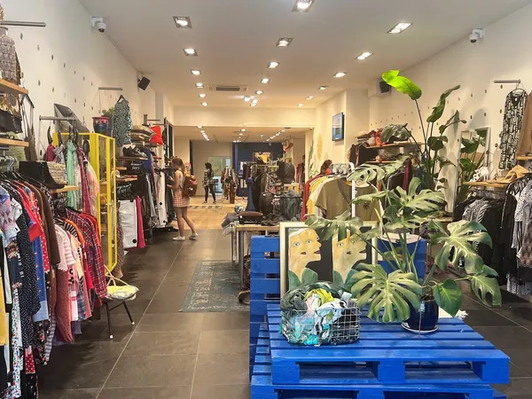 Winkelvloer met kledingrekken, blauwe pallets met planten en overzicht van het aanbod