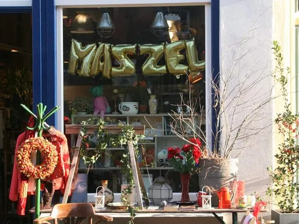 Winkelruit met gouden ballonletters 'MAZZEL', kerstkrans, rode lint en winterdecoratie in de etalage