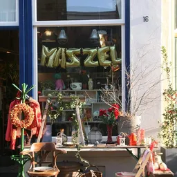 Winkelruit met gouden ballonletters 'MAZZEL', kerstkrans, rode lint en winterdecoratie in de etalage