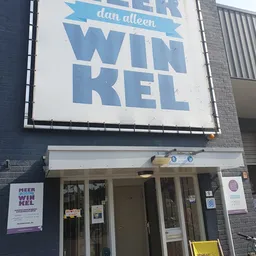 Gevel van kringloopwinkel Meerwinkel met blauwe letters op wit bord en winkelingang
