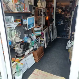 Winkelinterieur met stellingen, serviesgoed, decoratieve items en diverse tweedehands spullen langs de wanden