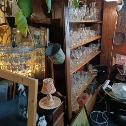 Glazen servies en kristallen glazen uitgestald op houten planken in de winkel