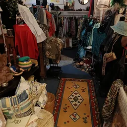 Winkelvloer met kledingrekken, vintage kleding en een decoratief kleed met geometrische patronen