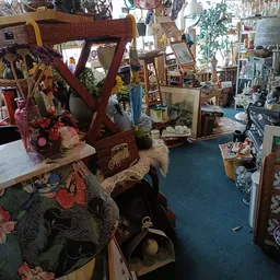 Winkelvloer met diverse tweedehandsartikelen, kunstbloemen, meubels en decorstukken op display