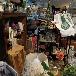 Verzameling huishoudelijke spullen en decoratie op planken en tafels in een kringloopwinkel