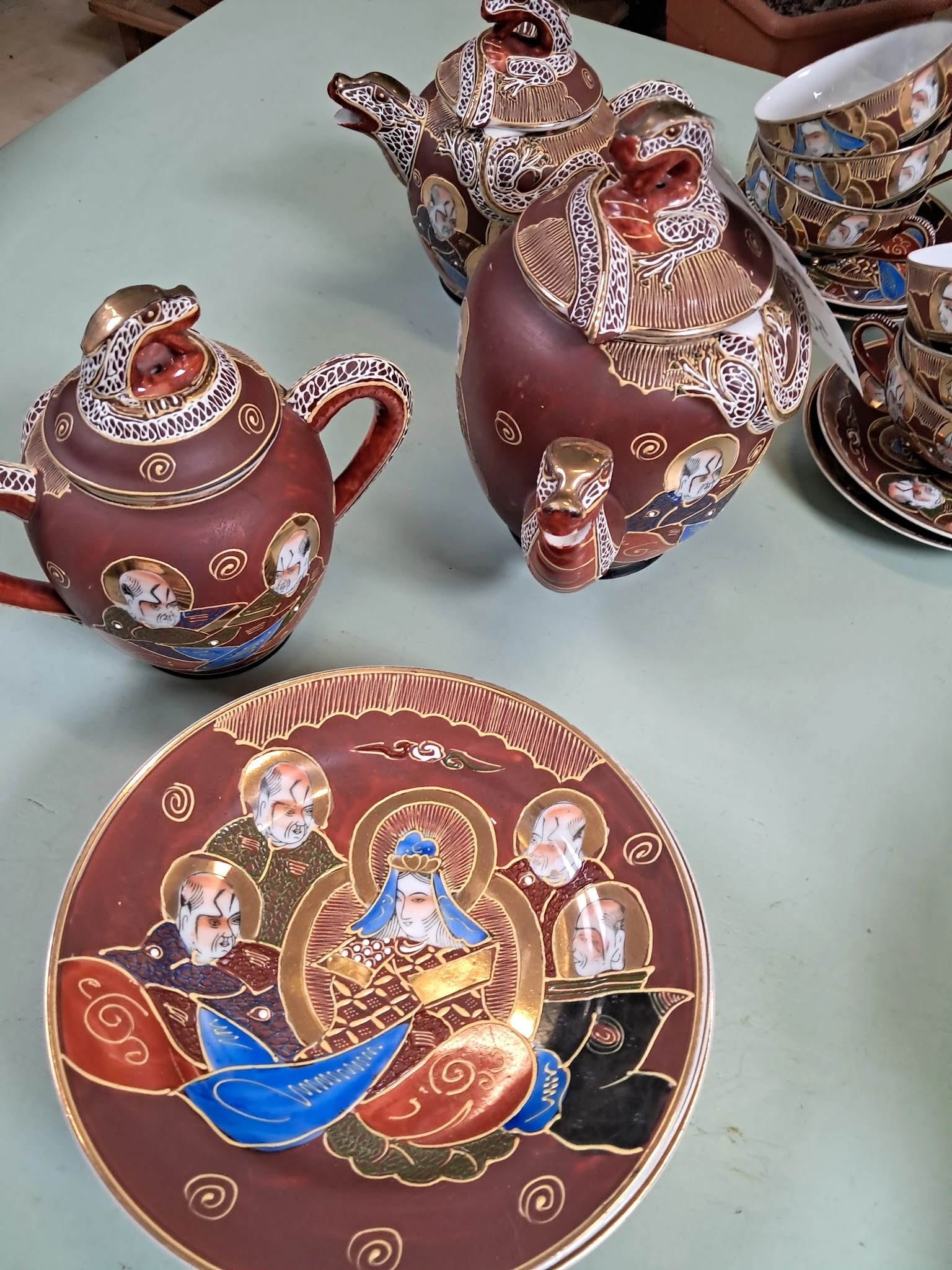 Rode porseleinen theepotten en bord met religieuze afbeeldingen en gouden decoratie