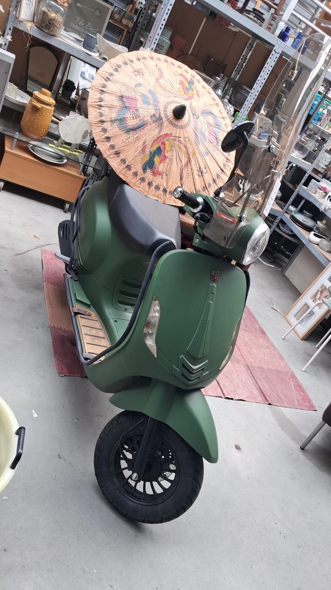 Groene Vespa-scooter in een kringloopwinkel, bovenaanzicht
