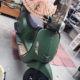 Groene Vespa-scooter in een kringloopwinkel, bovenaanzicht