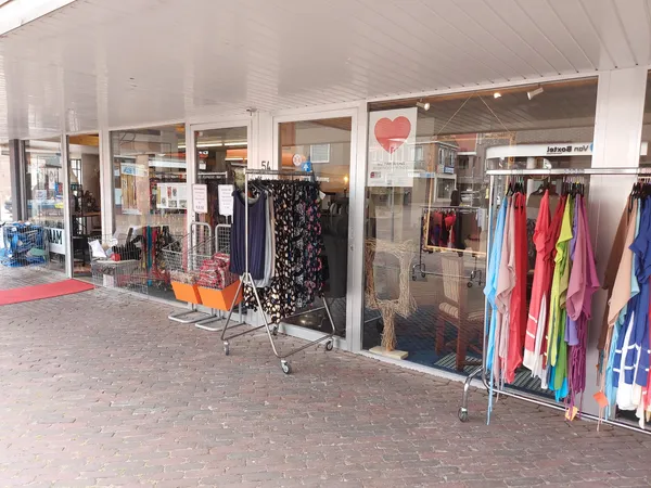 Winkelgevel met etalages vol kleding en een rood looppad aan de voorkant