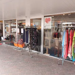 Winkelgevel met etalages vol kleding en een rood looppad aan de voorkant