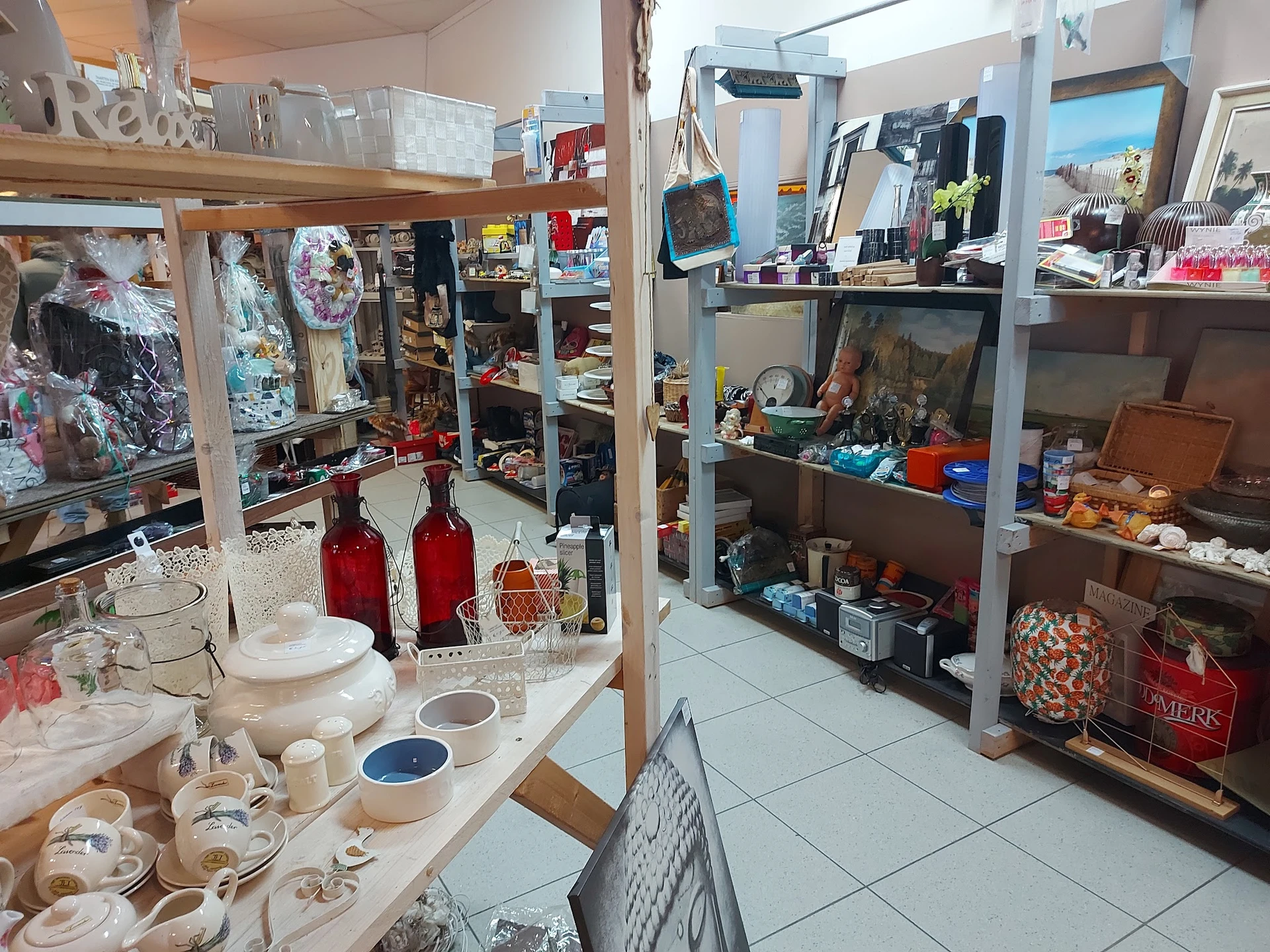 Binnenzicht van kringloopwinkel met stellingen vol huishoudwaar, servies, kasten en decoratieve artikelen