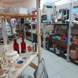 Binnenzicht van kringloopwinkel met stellingen vol huishoudwaar, servies, kasten en decoratieve artikelen