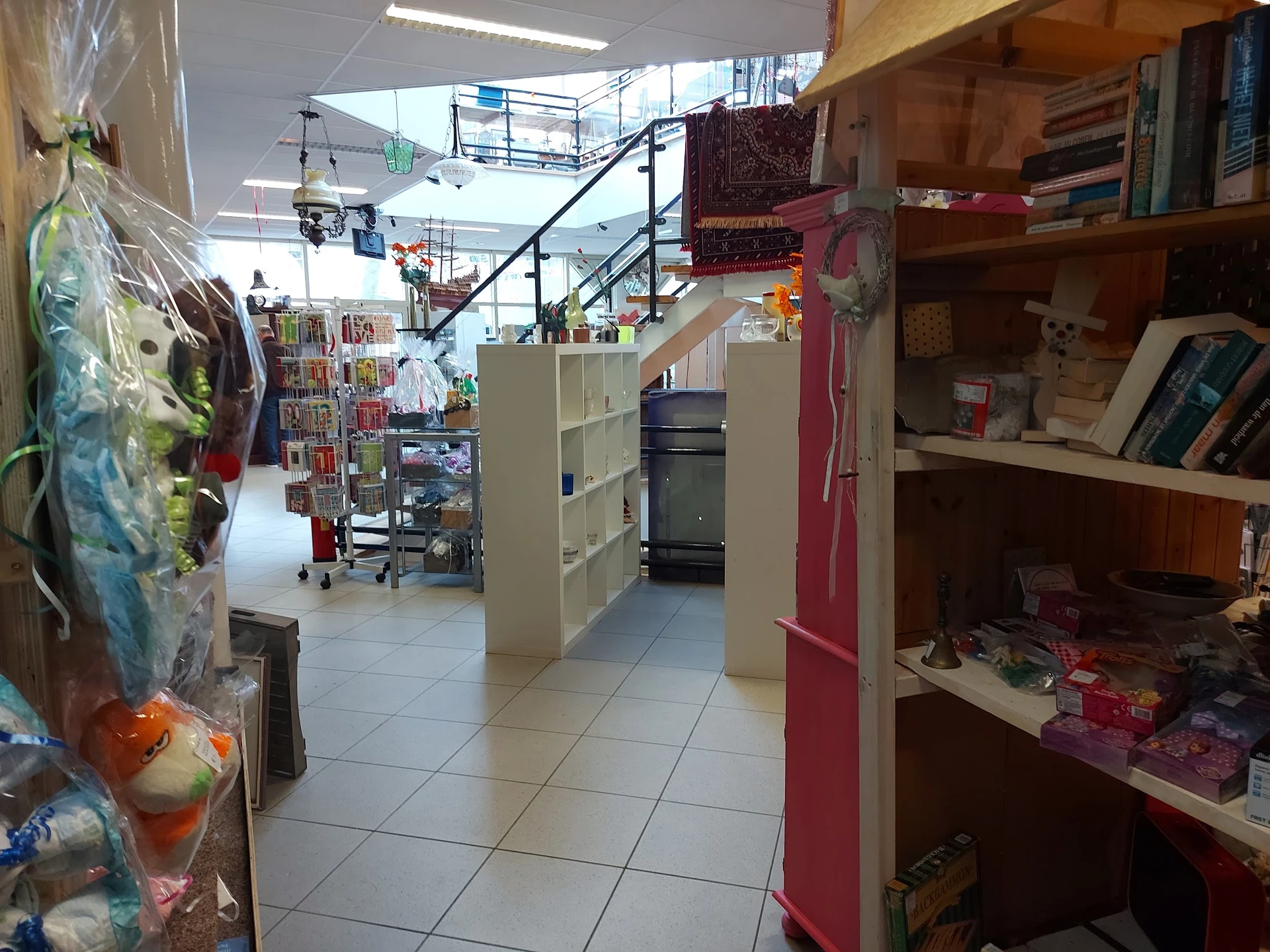 Winkelinterieur met stellingen, rekken en trap; zichtbaar aanbod van diverse tweedehandsartikelen