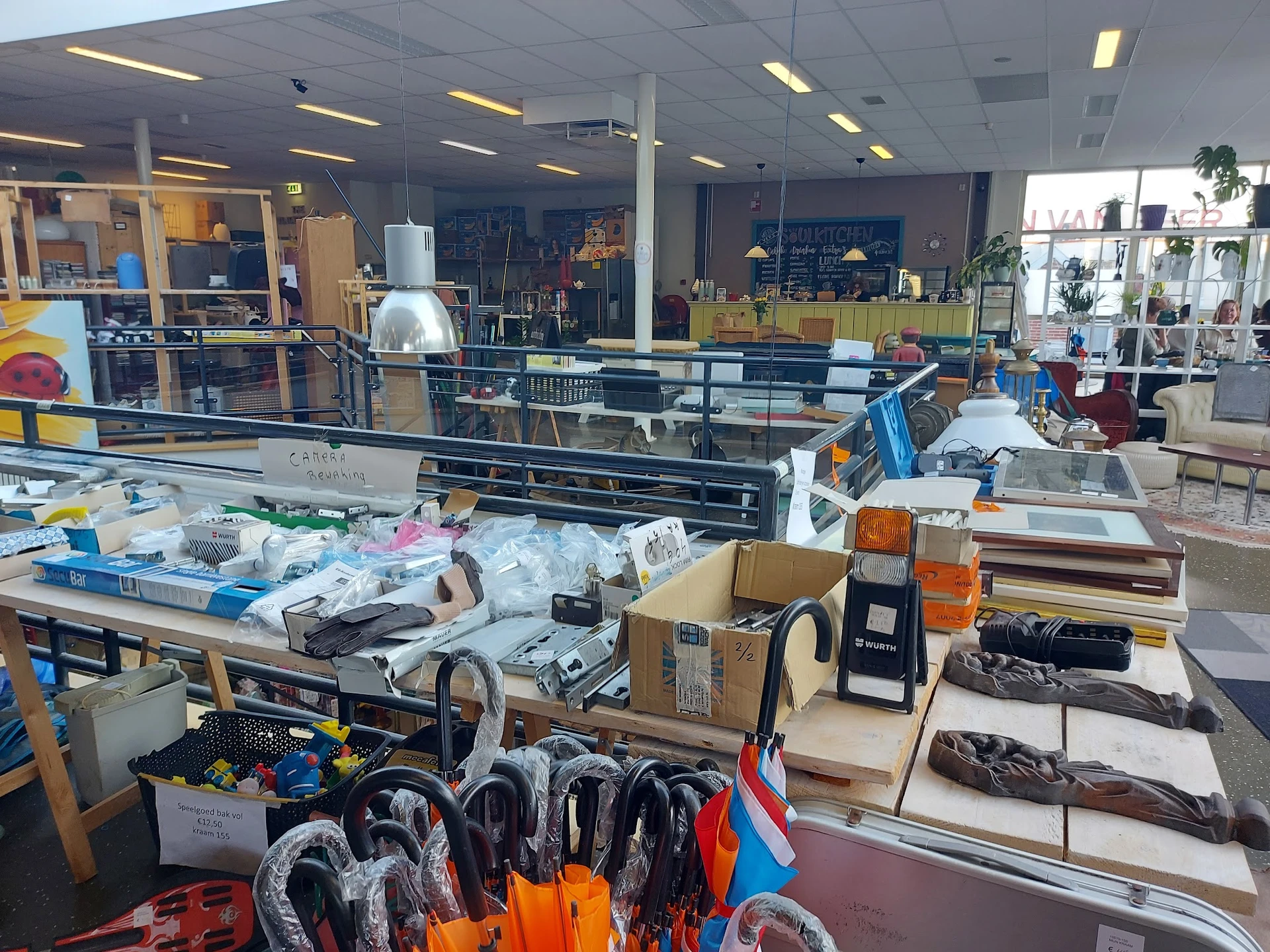 Overzicht van de winkelvloer met diverse uitgestalde spullen, stellingen en artikelen in een kringloopwinkel