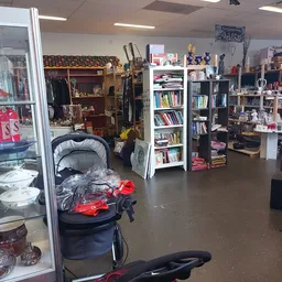 Winkelvloer van kringloopwinkel met stellingen, boeken, kinderwagen, huishoudspullen en diverse tweedehands goederen