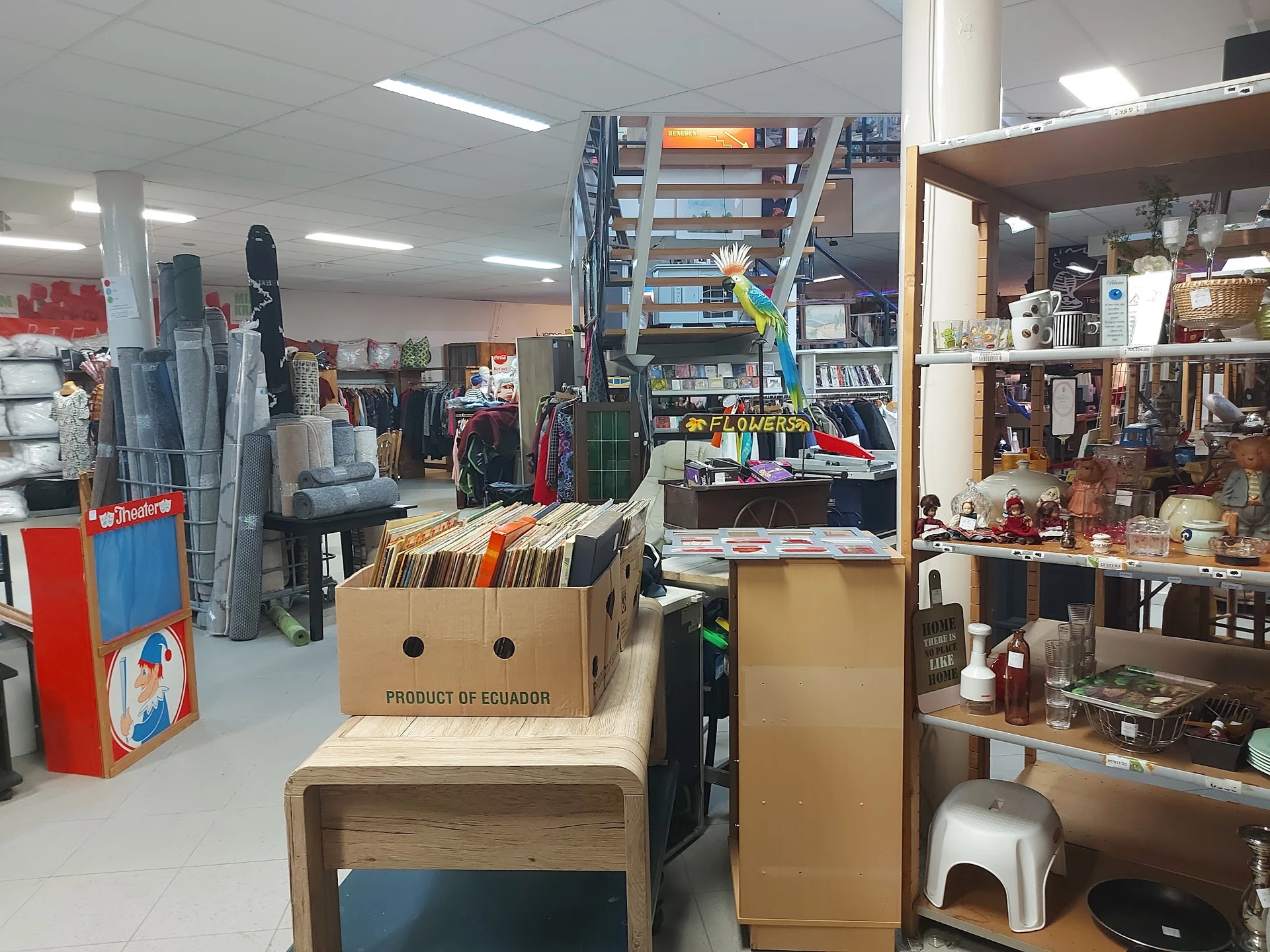 Winkelvloer met stellingen, rekken met kleding, dozen en diverse spullen in een kringloopwinkel