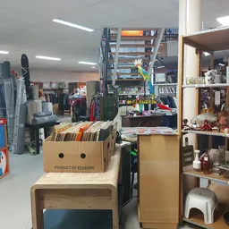 Winkelvloer met stellingen, rekken met kleding, dozen en diverse spullen in een kringloopwinkel