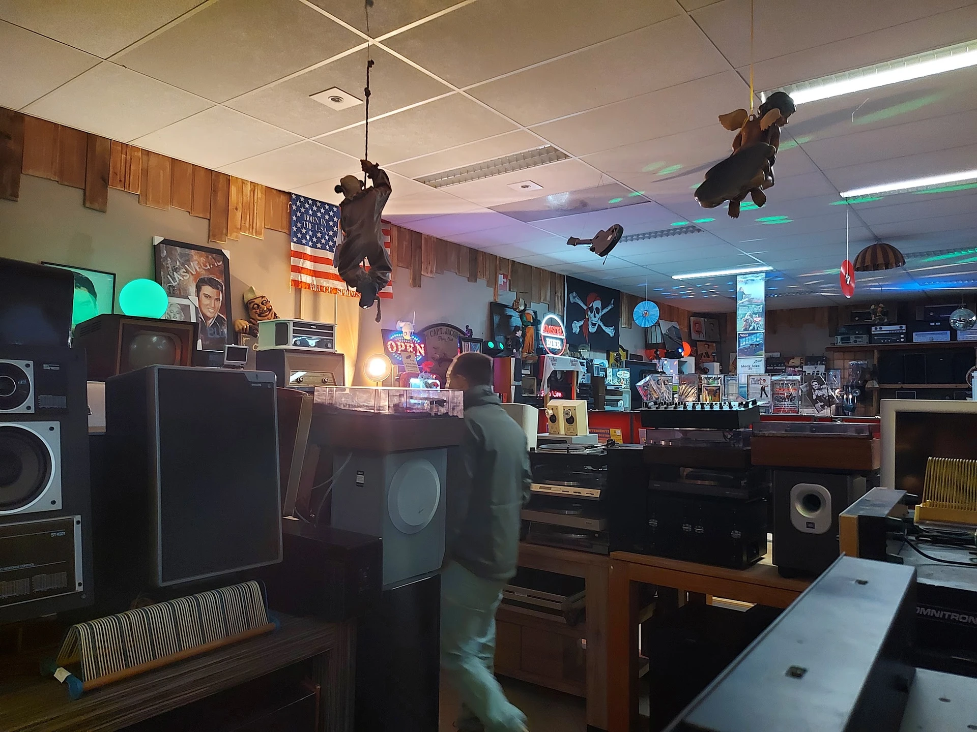 Interieur van kringloopwinkel met elektronicaartikelen, speakers, audio-apparatuur en diverse spullen op stellingen en tafels