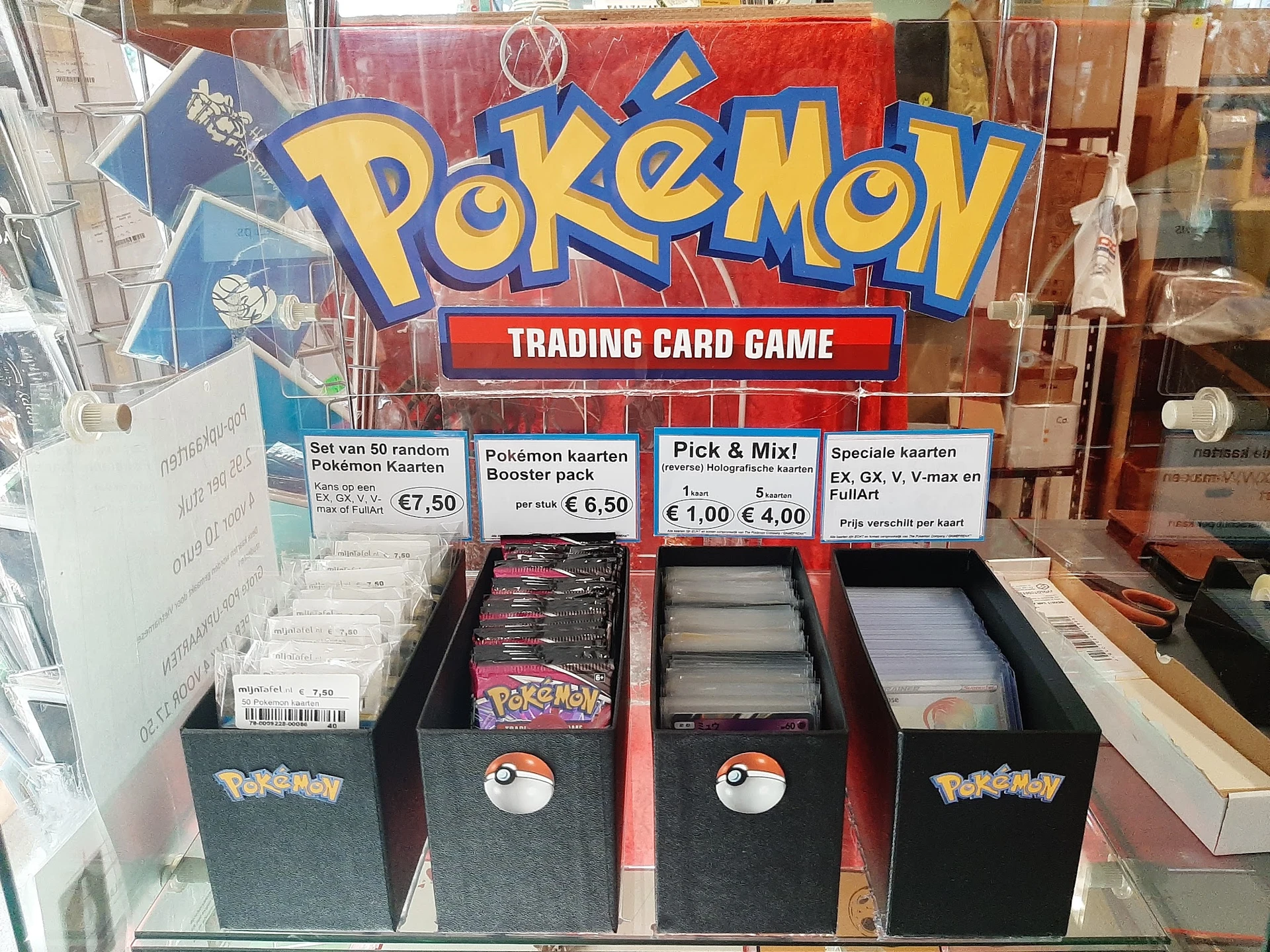 Uitstalling van Pokémon Trading Card Game producten in een kringloopwinkel met boosterpacks en kaarten in verschillende dozen