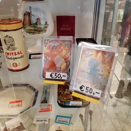 Vitrinekast met verzamelobjecten: vintage blikken, Pokemon-kaarten en andere collectibles met prijskaartjes.