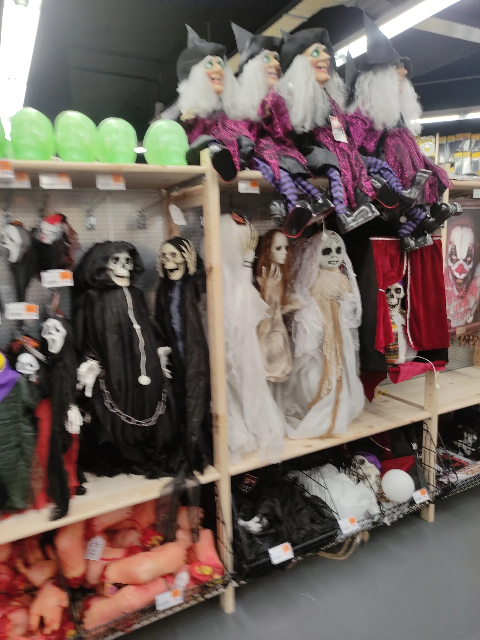 Uitgestalde Halloween- en griezelversiering met skeletpoppen en zwarte capes op een winkelrek